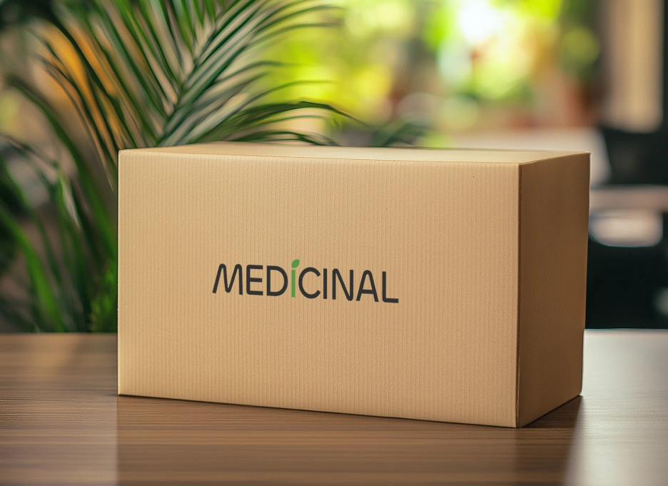 A cardboard box labeled "Medicinal" is placed on a wooden table, with a blurred plant and bright background.